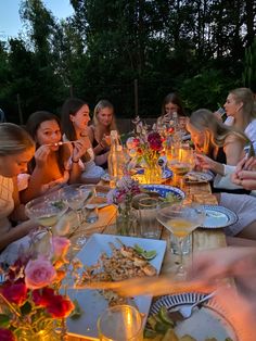 a group of people sitting around a table with food and drinks in front of them