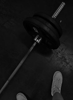 a person standing in front of a barbell with their feet propped up on the ground