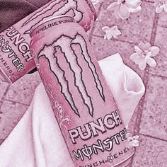 a pink monster energy drink sitting on top of a white towel next to a flower