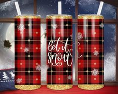 two red and black plaid christmas candles sitting on a window sill with snowflakes