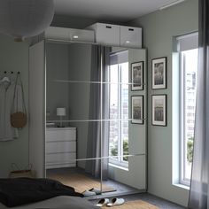 a bedroom with a large mirror on the wall next to a bed and dresser in front of two windows