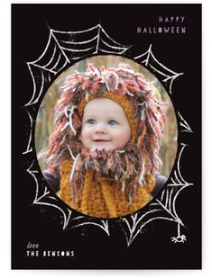 a card with a photo of a baby wearing a knitted hat and spider webs