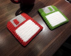 two crocheted coasters sitting on top of a wooden table next to a coffee mug