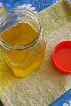 a glass jar filled with liquid sitting on top of a colorful table cloth next to a red plastic cup