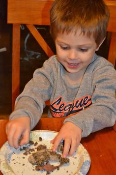 a little boy that is sitting at a table with some food in front of him