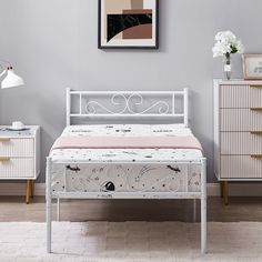 a white bed sitting next to a dresser with drawers on each side and a painting above it