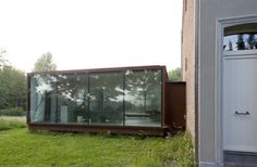 a glass house sitting on top of a lush green field