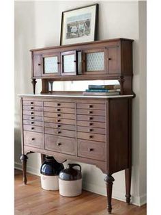 a large wooden dresser sitting next to a mirror on top of a white wall in front of a window