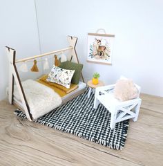 a dollhouse bedroom with white furniture and accessories on the wooden floor, including a bed