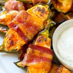 bacon wrapped jalapenos on a plate with ranch dip in the middle next to them