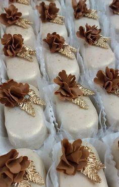 many white and brown decorated cookies in plastic wrappers with gold leaf decorations on them