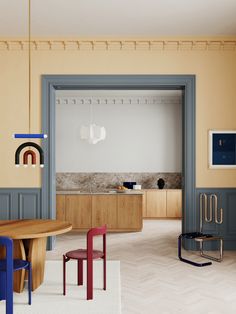 an open kitchen and dining room area with chairs, table, cabinets and artwork on the walls