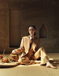 a woman sitting on the floor with food in front of her and wearing a suit