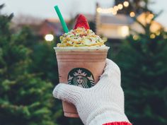 a hand holding up a starbucks drink with whipped cream and sprinkles in it