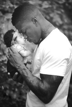 a man holding a baby in his arms and kissing it's face with the other hand