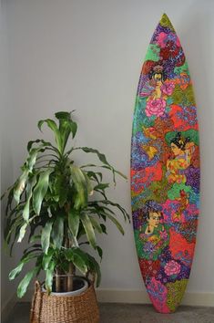 a colorful surfboard sitting next to a potted plant