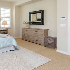 a bedroom with a large bed, dresser and mirror in it's center area