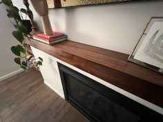 a fireplace with a wood mantle in the middle and a framed photograph on top of it