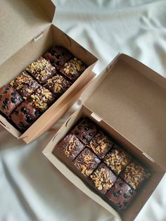 two boxes filled with brownies on top of a bed