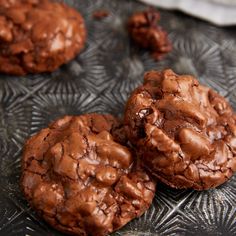 three chocolate cookies sitting on top of a glass plate