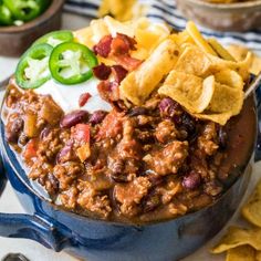 chili and beans in a blue pot with tortilla chips on the side next to it