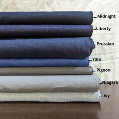 folded linens are stacked on top of each other, with the names of different fabrics