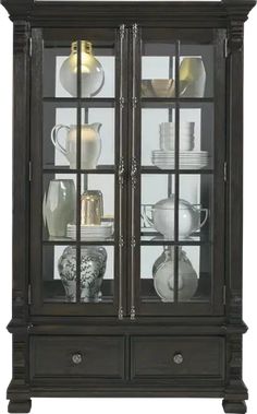 the china cabinet has glass doors and shelves with dishes on it's front shelf