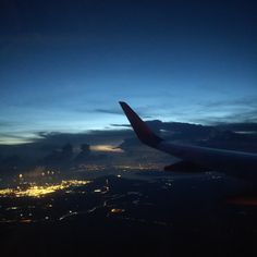 an airplane wing at night with the city lights in the background