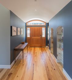 an entryway with wooden floors and blue walls, along with a wood door that leads to another room