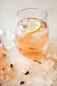 two glasses filled with ice and lemon on top of a table