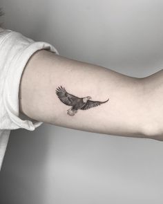 a woman's arm with an eagle tattoo on the left side of her arm