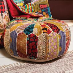 a colorful patchwork poufce sitting on top of a white floor next to a rug