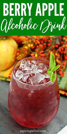 a close up of a drink in a glass on a table with apples and leaves