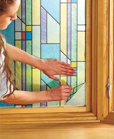 a woman is painting the side of a stained glass window with different colors and shapes