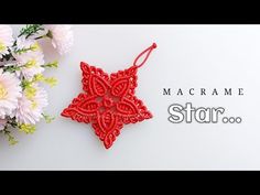 a red ornament sitting on top of a white table next to pink flowers