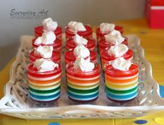 rainbow desserts with whipped cream on them sitting on a glass tray at a birthday party