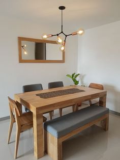 a dining room table with four chairs and a bench in front of the mirror on the wall