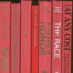 a row of red books sitting on top of a wooden shelf next to each other