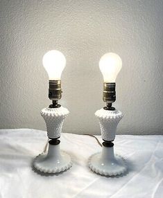 two white ceramic table lamps with one light turned on