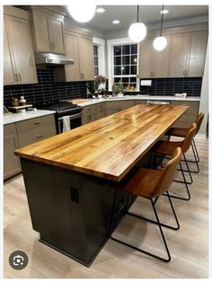 a kitchen with an island made out of wood and metal barstools in the center