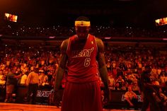 a basketball player standing on the court in front of an arena full of people and fans