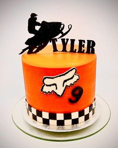 a birthday cake with an orange frosting and black lettering that says tyler on top