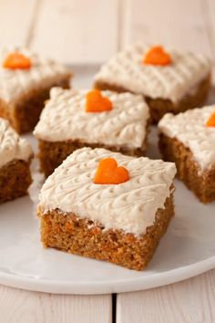 several pieces of carrot cake on a plate with white frosting and orange candies