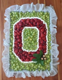 a cake made to look like the letter d is surrounded by grapes and green beans