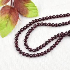 a long beaded necklace with a leaf on it