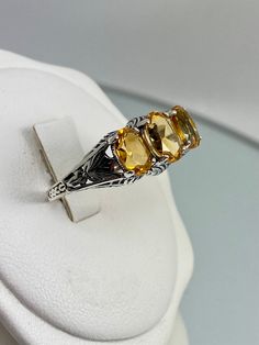 Natural Yellow Citrine 3Gem RingSmall 3Stone Design#D41 The Small 3Stone design #D41 is an elegant and exquisite filigree ring, made from sterling silver and inspired by Art Deco style designs. This high-quality cocktail ring is the perfect balance of classic beauty, vintage elegance, and modern grace. The triple stones of this ring – two 7x5mm side stones and one 8x6mm centerpiece – are expertly cut; they sparkle in the light, highly enhancing its glamour while also guaranteeing it won't go unn Yellow Topaz Ring As A Gift, Yellow Citrine Topaz Ring With Accent Stones, Yellow Citrine Rings With Accent Stones, Yellow Topaz Ring With Citrine Accent Stones, Formal Three Stone Yellow Jewelry, Formal Yellow Three Stone Jewelry, Yellow Three Stone Rings For Anniversary, Yellow Three Stone Anniversary Rings, Yellow Three Stone Ring For Gift