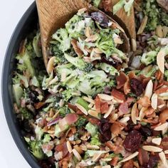 broccoli salad with cranberries and almonds in a black bowl on a white surface