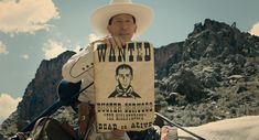 a man sitting on top of a horse holding a wanted sign