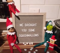 two elfs are sitting next to a sign that says, we brought you some squashmallows