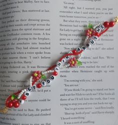 an open book with beads and charms on it's cover, in the shape of a cross